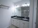 Bathroom with a double vanity, a large mirror, and a tiled shower at 5095 Southlawn Ave, Orlando, FL 32811