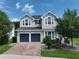 Charming two-story home featuring a brick driveway, blue garage doors and manicured landscaping at 5095 Southlawn Ave, Orlando, FL 32811