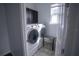 A functional laundry room featuring a modern washer and dryer, upper cabinets, and a natural light source at 5095 Southlawn Ave, Orlando, FL 32811