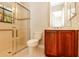 Well-lit bathroom with a glass-enclosed shower, a toilet, and a wood cabinet with a sink and a mirror at 154 Indian Wells Ave, Kissimmee, FL 34759