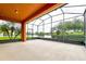 Spacious screened-in patio with a serene lake view surrounded by lush landscaping and swaying palm trees at 154 Indian Wells Ave, Kissimmee, FL 34759