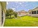 The backyard features a neatly mowed lawn, mature trees, and the home's exterior with siding and windows at 17567 Se 81St Parnassus Ct, The Villages, FL 32162