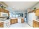 Open concept kitchen with wooden cabinets, white appliances, and a view to the living and dining areas at 17567 Se 81St Parnassus Ct, The Villages, FL 32162