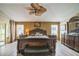 Spacious main bedroom featuring dark wood furniture, wood-look floors, ceiling fan, and natural light from windows at 17567 Se 81St Parnassus Ct, The Villages, FL 32162