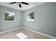 Cozy bedroom featuring wood floors, neutral walls, two windows, and a ceiling fan at 1304 E Myrtle St, Lakeland, FL 33801
