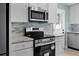 Bright kitchen features white cabinets, stainless steel appliances and complementing mosaic tile backsplash at 1304 E Myrtle St, Lakeland, FL 33801