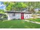 Home's exterior showcasing the red door, contrasted against lush lawn at 223 Pinehurst Dr, Auburndale, FL 33823