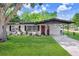 Charming single-story home with a well-manicured lawn and a welcoming red front door at 223 Pinehurst Dr, Auburndale, FL 33823