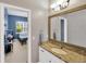 Granite countertop with wood framed mirror in bathroom with view of furnished bedroom at 2973 Blackwater Creek Dr, Lakeland, FL 33810