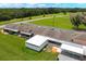 Aerial view of condo units with screened enclosures, expansive green spaces, and access road surrounded by trees at 4209 Club Cir, Lakeshore, FL 33854