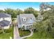 Aerial view of a beautiful blue home with manicured landscaping, brick drive, mature trees, and a lush green lawn at 2401 Lafayette Ave, Winter Park, FL 32789