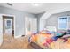 Bright bedroom with a colorful bedspread, plush carpet, and white loveseat near a window at 2401 Lafayette Ave, Winter Park, FL 32789