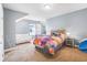 Bright bedroom with soft carpet, a colorful bedspread, and a comfortable loveseat next to a window at 2401 Lafayette Ave, Winter Park, FL 32789