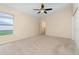 Sunlit bedroom with neutral carpet, ceiling fan, and a window overlooking the backyard at 3243 Winchester Estates Cir, Lakeland, FL 33810