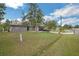 Exterior view showcasing a home's front yard, lush lawn, mature trees, and extended driveway at 107 Talavera Ln, Kissimmee, FL 34758