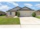 Charming single-story home featuring a two-car garage, manicured lawn, and neutral stucco exterior at 1741 Canaan Loop, Dundee, FL 33838