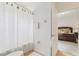 Bright bathroom with white walls, tile floor, a shower with curtain, and view into the main bedroom at 448 Sorrento Rd, Kissimmee, FL 34759