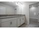 Bathroom featuring double sinks, white cabinetry, and an adjoining tub/shower at 8875 Backspin Ln, Champions Gate, FL 33896