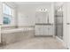 Bathroom featuring a large tub, glass shower, and double vanity with neutral tile at 8875 Backspin Ln, Champions Gate, FL 33896