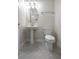 Small bathroom featuring a pedestal sink, toilet, oval mirror, and neutral tile flooring at 8875 Backspin Ln, Champions Gate, FL 33896