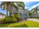 Charming two-story home boasts a stone-accented facade, gray palette, lush landscaping, and a paved driveway at 8875 Backspin Ln, Champions Gate, FL 33896
