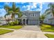 Charming two-story home boasts a stone-accented facade, gray palette, lush landscaping, and a paved driveway at 8875 Backspin Ln, Champions Gate, FL 33896
