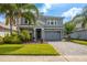 Charming two-story home boasts a stone-accented facade, gray palette, lush landscaping, and a paved driveway at 8875 Backspin Ln, Champions Gate, FL 33896