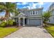 Charming two-story home boasts a stone-accented facade, gray palette, lush landscaping, and a paved driveway at 8875 Backspin Ln, Champions Gate, FL 33896