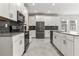 Modern kitchen with white cabinets, stainless steel appliances, island, and dark backsplash at 8875 Backspin Ln, Champions Gate, FL 33896