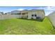 Expansive backyard with green grass, covered patio, and white vinyl fence at 1335 Berry Ln, Davenport, FL 33837