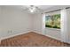 Empty bedroom with neutral walls, plush carpeting, and a bright window overlooking the yard at 2825 Woodcrest Ln, Lakeland, FL 33805