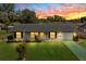 Charming single-story home with well-manicured lawn, flower beds, and colorful sunset sky at 2825 Woodcrest Ln, Lakeland, FL 33805