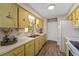 Bright kitchen with wood-look tile flooring and light green cabinets, featuring a white refrigerator and stove at 2825 Woodcrest Ln, Lakeland, FL 33805