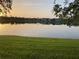Scenic view of a tranquil pond reflecting the sky, surrounded by lush green grass and distant houses at 9053 Lee Vista Blvd # 1405, Orlando, FL 32829
