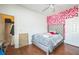 Bright bedroom features wood floors, a tufted headboard, and a striking wall covered in vibrant floral decorations at 4931 Jetton Dr, Orlando, FL 32837