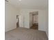 Spacious bedroom featuring neutral carpet, white walls and trim, and an open doorway to the stairs and bathroom at 4444 Withrowwood Ct, Orlando, FL 32837