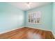 A cozy bedroom featuring a ceiling fan, wood floors, and a large window that provides natural light at 9349 Mira Valle Ln, Winter Garden, FL 34787