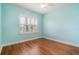 Cozy bedroom featuring blue walls, hardwood floors, and a large window with blinds at 9349 Mira Valle Ln, Winter Garden, FL 34787