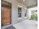 Elegant front door with iron hardware, flanked by windows on a covered porch at 9349 Mira Valle Ln, Winter Garden, FL 34787