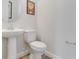 Modern half bathroom featuring a pedestal sink, round mirror, and ceramic toilet at 2132 Limestone Trl, Kissimmee, FL 34747