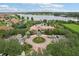 Aerial view of grand community clubhouse with manicured gardens, circular driveway, and lake backdrop at 4235 Prima Lago Dr, Lakeland, FL 33810