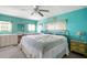 Turquoise bedroom featuring a brass bedframe, ceiling fan and a vanity set under a large window at 932 Cassandra Ln, Lakeland, FL 33809