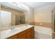 Well-lit bathroom offering double sinks, a bathtub, and a glass door shower at 504 Mirasol Cir # 102, Kissimmee, FL 34747