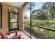 Screened-in patio featuring comfortable red Adirondack chairs and a tranquil view of the pond at 504 Mirasol Cir # 102, Kissimmee, FL 34747