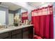 Elegant bathroom with a double sink vanity, granite countertop, and stylish red shower curtain at 5934 Shingle Creek Rd, Lakeland, FL 33811