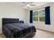 Bedroom with a modern black bed, ceiling fan, and a large window with blue curtains at 8628 Sw 133Rd Lane Rd, Ocala, FL 34473