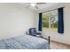 Cozy bedroom with a blue bedspread, ceiling fan, and a window with a view of green trees at 8628 Sw 133Rd Lane Rd, Ocala, FL 34473