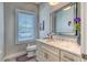 Well-lit bathroom featuring a modern vanity with granite countertop, framed mirror, and a window with blinds at 12902 Sw 138Th Loop, Dunnellon, FL 34432