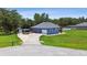 Blue home featuring a large garage, long driveway, and lush green lawn at 3229 Gardner Oaks Ln, Lakeland, FL 33810