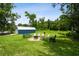 Landscaped backyard with a metal outbuilding, firepit area, and benches and chairs at 3229 Gardner Oaks Ln, Lakeland, FL 33810